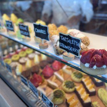 Vetrina di pasticceria con tartellette alla fragola e dolci assortiti etichettati con cartellini neri